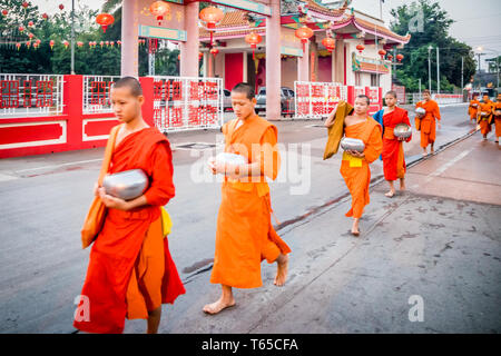 Mae Sot, Thailand - 3. Februar 2019: Junge Mönche zu Fuß in einer Linie hinter chinesischen Tempel. Mönche sammeln Almosen jeden Morgen. Stockfoto