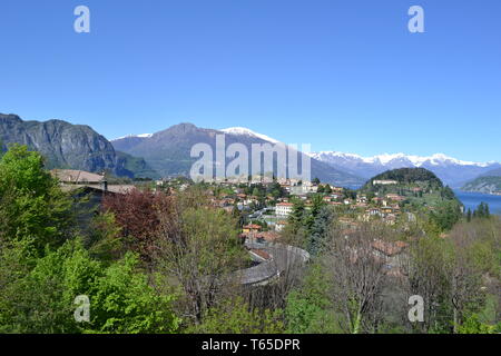 Schöner Frühling Blick auf Bellagio Halbinsel mit einer Stadt, die Europäischen Alpen mit Schnee über Gipfel und den Comer See von der Straße nach Lecco an einem sonnigen Tag. Stockfoto