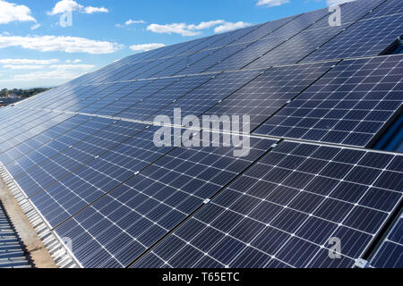 Solarzellen auf einem Dach mit blauem Himmel und weißen Wolken Hintergrund Stockfoto