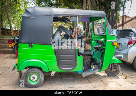 Der Fahrer eines hellen grünen Tuk Tuk seine Füße setzt oben und nimmt einen Bruch in der Sri-lankischen Stadt Galle. Stockfoto