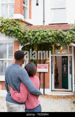 Glückliches Paar umarmen außerhalb neues Haus Stockfoto