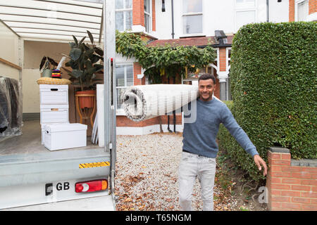 Portrait zuversichtlich Mann, der Teppich außerhalb Umzugswagen, Umzug Stockfoto