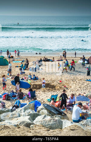 Urlauber genießen die Sonne auf einer belebten Fistral Beach in Newquay in Cornwall. Stockfoto