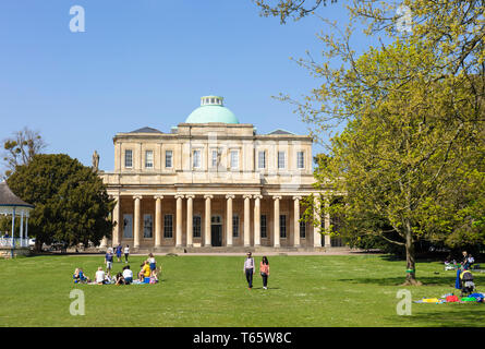 Cheltenham Pittville Pump Room mit Menschen bei einem Picknick und spielende Kinder Pittville Park, Cheltenham Spa Gloucestershire, England, UK, GB, Europa Stockfoto