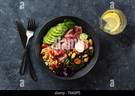 Gesundes Essen buddha Schüssel mit Rindersteak, Bohnen, Couscous, Avocado und Gemüse Stockfoto