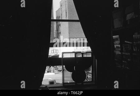Hohe Betrachtungswinkel und einer Stadt, aus der Perspektive der oberen Etagen Fenster mit teilweise offenen Vorhängen und einem elektrischen Ventilator auf den Fenstersims, Washington, District of Columbia, 9. Mai 1970 thront. () Stockfoto