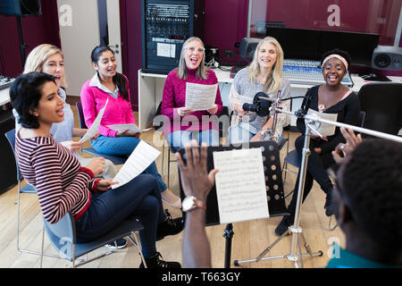 Männliche Leiter der führenden Frauen Chor mit Noten singen in Music Recording Studio Stockfoto