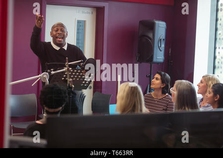 Männliche Leiter führenden Frauen singen in Music Recording Studio Stockfoto