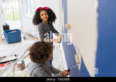 Portrait Happy girl painting wall mit Bruder Stockfoto