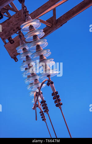 Elektrische Isolatoren aus Glas auf elektrische Leitung gegen den blauen Himmel mit Copyspace Stockfoto