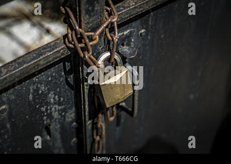 rostige Kette auf einer Metalltür mit Vorhängeschloss Stockfoto