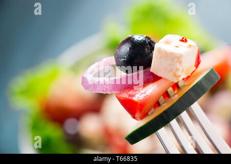 Nahaufnahme von griechischer Salat mit Tomaten, Gurken, Zwiebeln, Schafskäse und schwarzen Oliven in einer Gabel Stockfoto