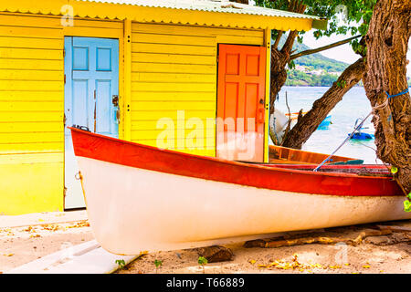 Sehr schönes, helles Gelb Orange Blau Holz- Haus am Strand mit bunten Holz mit roten Boot vor und. Karibik, Travel Concept Stockfoto