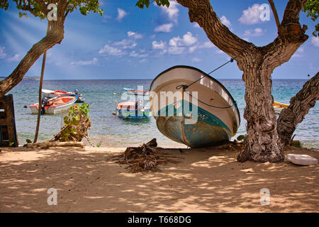 Kleine bunte Boote auf kristallklarem Wasser Ozean und einem Boot am Strand, an der goldenen Zeit mit Strahl der Sonne Licht. Travel Concept Stockfoto