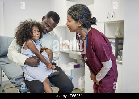 Weibliche Kinderarzt im Gespräch mit Vater und Tochter in der Klinik Untersuchungsraum Stockfoto