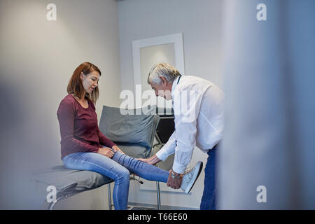 Männlicher Arzt womans Prüfung Bein in der Klinik Untersuchungsraum Stockfoto