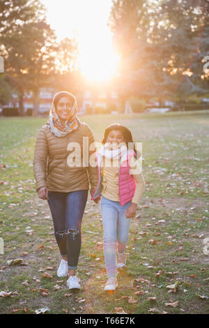 Portrait happy muslimische Mutter und Tochter wandern im sonnigen Herbst Park Stockfoto