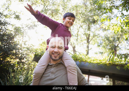 Portrait verspielt Vater mit Sohn auf Schultern in Park Stockfoto