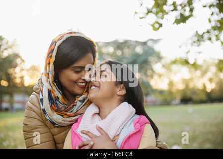 Zärtlich, glücklich muslimische Mutter im hijab umarmen Tochter im Herbst Park Stockfoto