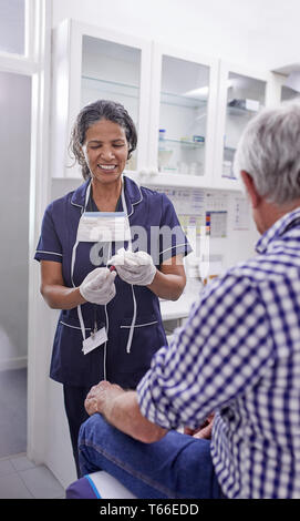 Ärztin nehmen Blut vom älteren männlichen Patienten in der Klinik Untersuchungsraum Stockfoto