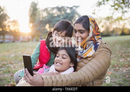 Muslimische Mutter im hijab unter selfie mit Kamera Handy im Herbst Park Stockfoto