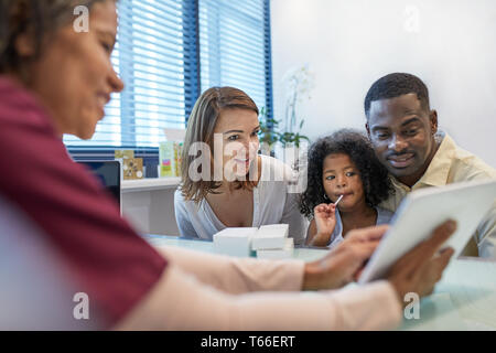 Arzt mit digitalen Tablet im Gespräch mit Familie im Doktorbüro Stockfoto