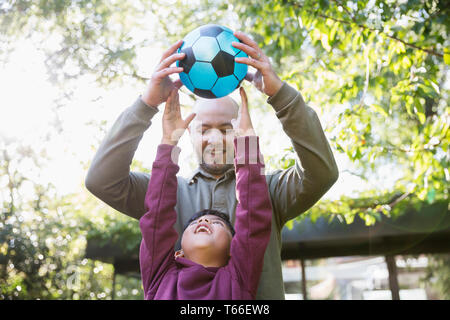 Vater und Sohn Fußball spielen im sonnigen Park Stockfoto