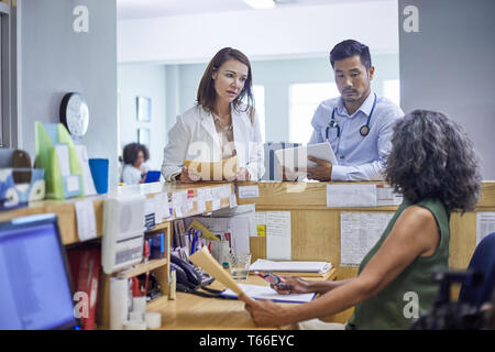 Ärzte und Angestellte an der Rezeption sprechen in Klinik Stockfoto