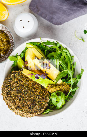 Grüner Salat mit Avocado grüne vegane Schnitzel, Rucola und Pesto in einem grauen Schale. Gesunde vegane Ernährung Konzept. Stockfoto