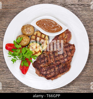 Gegrillte Steaks, gebackenen Kartoffeln und Gemüse auf w Stockfoto