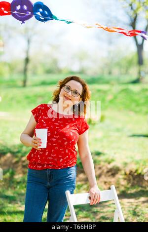 Die Frau im roten Kleid trinken auf Garden Party - positive Energie Stockfoto