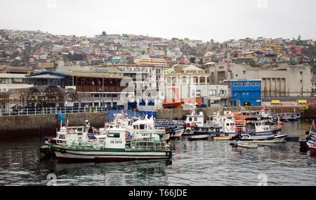 Kleine und mittlere Boote im Hafen im historischen Hafen von Valparaiso in Chile; die Stadt liegt am Hang über Stockfoto