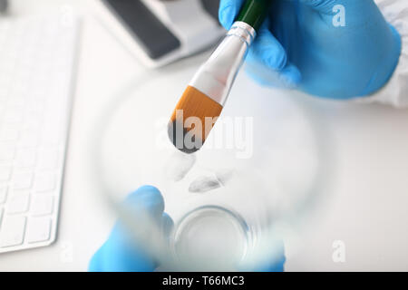 Männliche Hand in blu Schutzhandschuhe halten Sie die Bürste Stockfoto