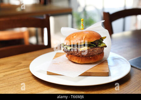 Appetitlich Beef Burger mit grünem Gemüse auf einem Holzbrett serviert. Vorschlag Vorschlag, Menü. Horizontale Zusammensetzung Stockfoto