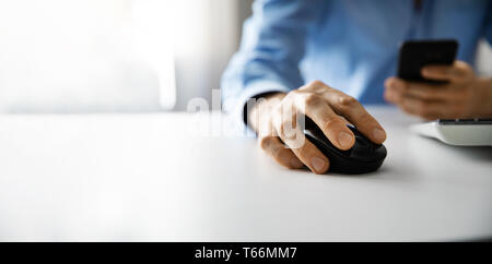 Mann bei der Arbeit mit Desktop Computers und die Verwendung von Smart Phone im Büro. Kopieren Sie Platz Stockfoto