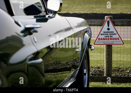 Warnung Motor Sport kann gefährliche Zeichen an der Rennstrecke Zaun entlang der Lavant gerade Anzeigebereich am 77. Goodwood GRRC Mitglieder treffen werden, Großbritannien Stockfoto