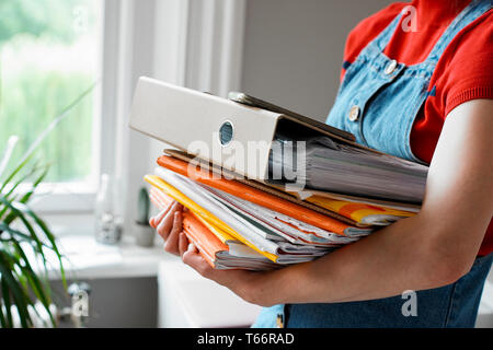 Junge weibliche Studenten, die Stapel von Büchern und Binder Stockfoto