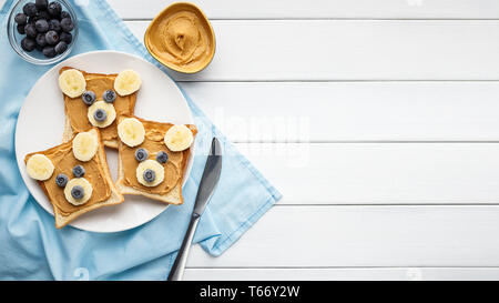 Lustige Sandwiches mit Erdnussbutter auf Platte auf weißem Holz- Hintergrund diente, Ansicht von oben, kopieren. Amerikanische dessert Konzept Stockfoto