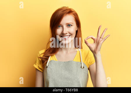 Fröhliches glückliches Mädchen zeigen ok Zeichen als große Vertriebskonzept auf gelbem Hintergrund. nach oben Porträt schließen. Glück, gute Arbeit, ist alles ok. Stockfoto