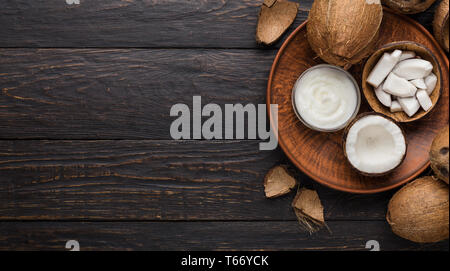 Ganze Kokosnuss, coco Zellstoff- und Butter auf der Platte über Holz- hintergrund Gehackt, Ansicht von oben, kopieren. Stockfoto