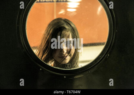 Mädchen schauen durch ein rundes Fenster Stockfoto