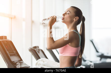 Rest nach der Ausführung. Frau trinkt Wasser, Ausübung auf Laufband im Fitnessstudio Stockfoto