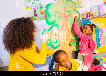 Lehrer mit Kindern Buchstaben auf dem Baum im Alphabet Spiel im Kindergarten Stockfoto