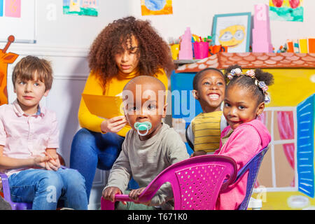 Toddler mit Schnuller in der Gruppe der Kinder im Kindergarten ernst in die Kamera schauen Stockfoto