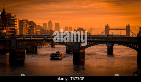 Sonnenaufgang über der Themse und die Southwark Bridge mit Tower Bridge und die Docklands, Canary Wharf in der Ferne. Stockfoto