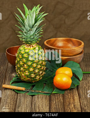 Stilleben mit Ananas und Orangen auf Holz- Hintergrund. Stockfoto