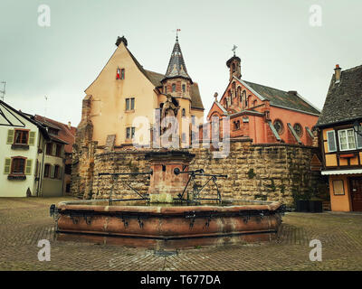 Schloss, Kirche und Brunnen namens Saint Leon auf dem zentralen Platz von Eguisheim Dorf im Elsass, Frankreich. Stockfoto