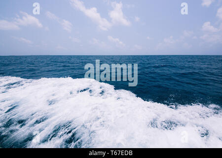 Blaue Wasser Hintergrund mit Wellen. Nahaufnahme Natur Hintergrund. Soft Focus mit selektiven Fokus. Wellen hinter einem Boot auf einem ruhigen Meer. Stockfoto
