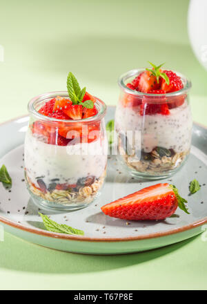 Joghurt Müsli Parfait mit Erdbeeren und Chia Samen. Gesund leckeres Dessert für das Frühstück. Mint Green Hell Frühling Sommer Hintergrund Stockfoto