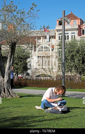 Jardim das Oliveiras Frau sitzt von olivenbaum Blick auf Handy außen Lello Buchladen Gebäude Praça de Lisboa Porto Portugal KATHY DEWITT Stockfoto